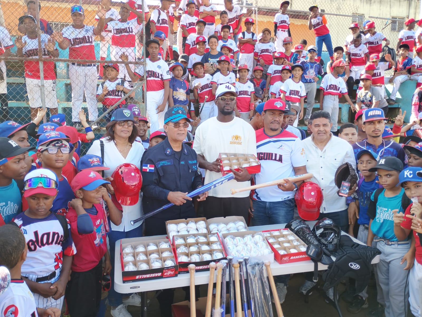 Diógenes De la Cruz, asistente de Junior Noboa, Comisionado de Béisbol, al momento de hacer entrega de utilería a la Liga Domingo Morel de Cristo Rey. Figura Ronny Mauricio, del Licey , el general Jacobo Mateo Moquete, Director de Deportes de la Policía, Domingo Morel, así como los decenas de niños participantes.