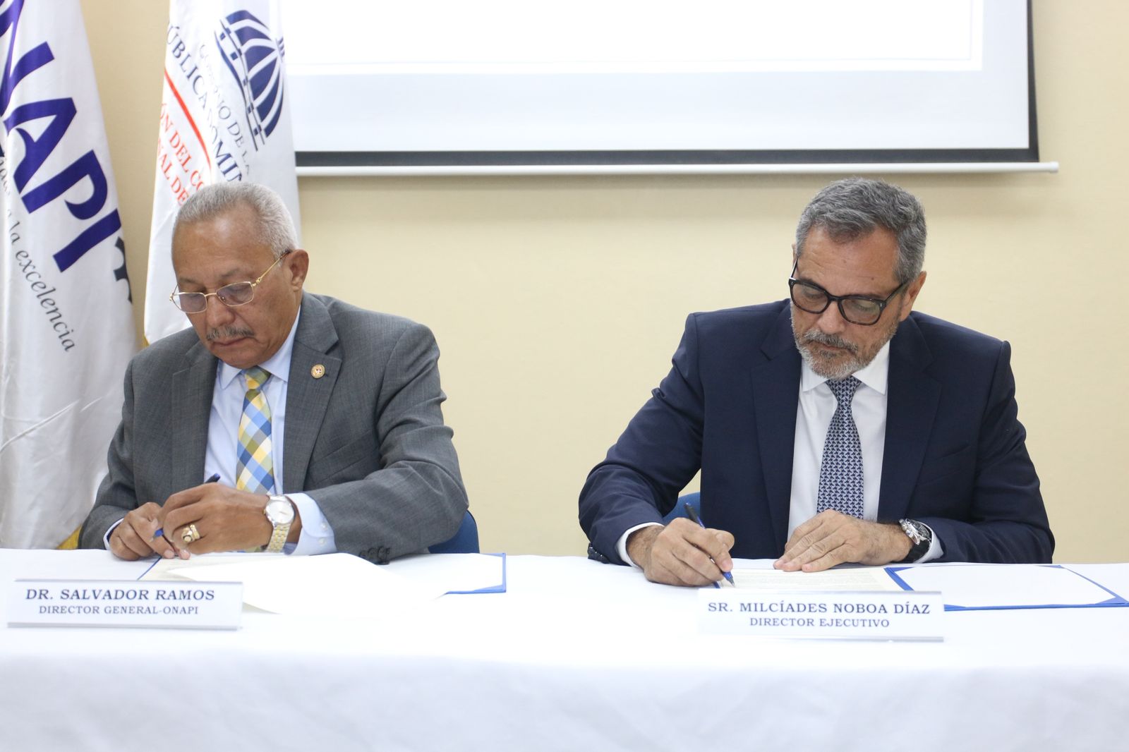 La Dirección del Comisionado Nacional de Béisbol (DCNB) y la Oficina Nacional de la Propiedad Intelectual (ONAPI) suscribieron un acuerdo de colaboración con la finalidad de lograr un mayor desarrollo integral del sector deportivo para la promoción, capacitación y formación de las academias independientes, así como los programas y ligas de béisbol. El pacto fue firmado por el exgrandesligas, Junior Noboa, director de la DCNB y el doctor Salvador Ramos, Director General de ONAPI en la realización de un encuentro efectuado en la sede central de esta última institución este viernes. “Somos el único país con academias de las 30 organizaciones de Grandes Ligas, además de miles de programas. Nuestra meta más importante es poder desarrollar buenos ciudadanos. Existe una cantidad de academias y ligas que necesitamos registrar y por eso es tan importante este acuerdo con ONAPI, a los fines de tener una mejor industria. Gracias al director Salvador Ramos por recibirnos y por la oportunidad de que exista mejor organización para nuestros niños y jóvenes”, expresó el director Noboa. Acto seguido, el doctor Ramos tomó la palabra para expresar el significado que tiene el acuerdo para la entidad que dirige. “Para ONAPI constituye un paso importantísimo la firma de este acuerdo. No podemos quedar detrás con el significado que tiene el vínculo con la actividad deportiva, y de manera especial con el béisbol. Podemos hacer bastante de manera conjunta, llevando capacitación con relación a lo que es la propiedad industrial. Vamos a seguir estrechando más los lazos para obtener mayor desarrollo: trabajar juntos es trabajar para el país”, expuso el doctor Ramos. Tras la rúbrica, ONAPI se compromete a otorgar un descuento de un 25 por ciento sobre la tasa ordinaria aplicable a los trámites de registros de nombres comerciales, marcas, rótulos, lemas comerciales y demás signos distintivos a favor de las academias independientes, programas y ligas de béisbol que estén debidamente reconocidas por la DCNB. Dicho descuento será concedido de manera exclusiva para los organismos de béisbol mencionados que presenten junto a su solicitud una copia del registro de incorporación al sistema de béisbol vigente emitido por la DCNB, que lo acredite como entidad reconocida. En ese sentido, ONAPI se encargará de validar esta certificación conforme a sus protocolos internos antes de dejar con validez el mencionado descuento. El convenio tendrá una vigencia de dos años contados a partir de la firma y ambas entidades acordaron que si llegado al término del mismo ninguna de ellas denunciare su intención de renovar el mismo quedará renovado de manera automática por un plazo igual al vencido. Cabe mencionar que este beneficio será personal e intransferible por lo que no podrá cederse ni aplicarse a otros trámites distintos a los expresamente citados en esta cláusula. ONAPI también ofrecerá asistencia técnica y un acompañamiento especializado en materia de propiedad industrial a las academias independientes, programas de capacitación y las ligas de béisbol. Tanto la DCNB como ONAPI se comprometen a unir todos los esfuerzos y utilizar las relaciones que tengan a su alcance para dar cumplimiento al objetivo del recién firmado convenio. Para las dos instituciones será una responsabilidad conjunta el promocionar las actividades que realicen en el marco de la presente alianza. El uso de logotipos, emblemas o imagen institucional de una parte en actividades, publicaciones o comunicaciones derivadas del mismo requerirá una aprobación escrita y previa de la otra parte. Además de los directores de ambas entidades, durante el encuentro hicieron acto de presencia por la DCNB los señores Carlos Solano, encargado del Departamento Jurídico, Fernando Ramírez, encargado del Departamento de Educación, Rosa María de la Cruz Yeb, directora de la Dirección de Regulación del Sistema de Béisbol y Luis Fernando Taveras Díaz, encargado del Departamento de Asistencia Legal. Por Onapi, estuvieron presentes Ángel Veras, Director Jurídico, Juan Toribio, Asesor de la Dirección, Luisa Castillo, Directora de Inversiones, Michelle Guzmán, Directora de Signos Distintivos, Narcis Tejada, Encargada de la Academia Nacional de Propiedad Intelectual, Emely Martínez, Encargada de Relaciones Internacionales e interinstitucionales, LisibelCordero, Encargada de Proyectos y Rosa Almonte, Encargada de Planificación y Desarrollo. SOBRE LA DCNB La Dirección del Comisionado Nacional de Béisbol (DCNB) secreó en 2023 mediante el decreto 691-23. Su misión es promover y desarrollar el béisbol dominicano en todas sus áreas, desde las categorías menores hasta las Grandes Ligas, con el objetivo de fortalecer la institucionalidad, la transparencia y la rendición de cuentas, para asegurar la sostenibilidad del béisbol como un patrimonio cultural y deportivo de la nación.